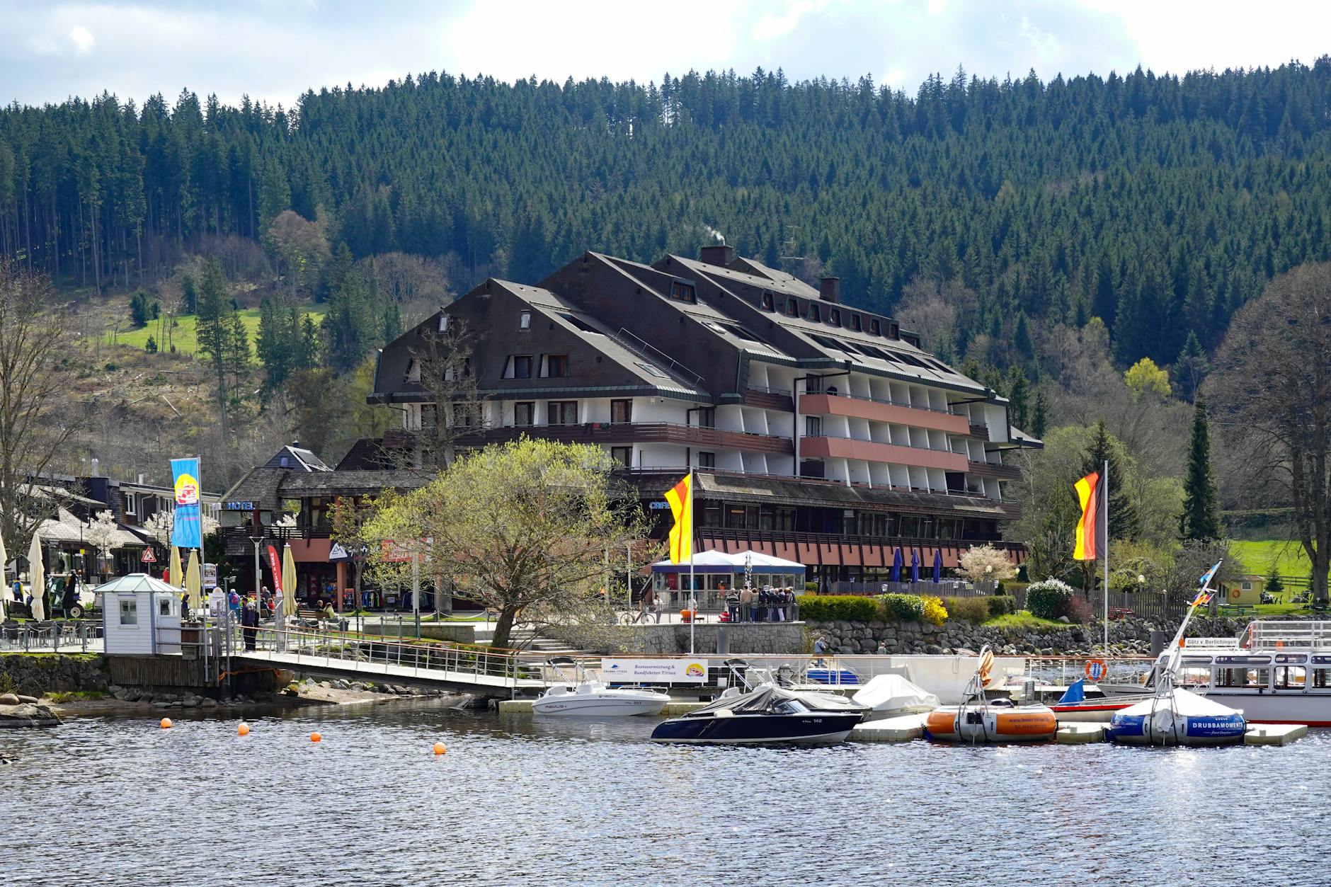 Picturesque lakeside hotel with boats by a lush forest, ideal for travel inspiration.