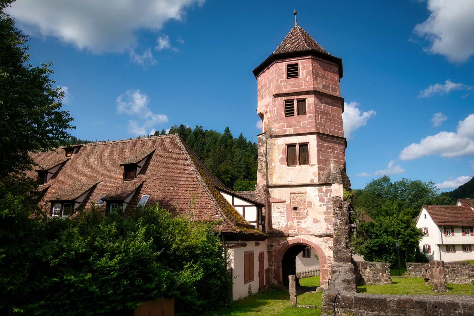 Captured in Calw, Germany, this historic tower stands against a vivid blue sky surrounded by lush greenery.